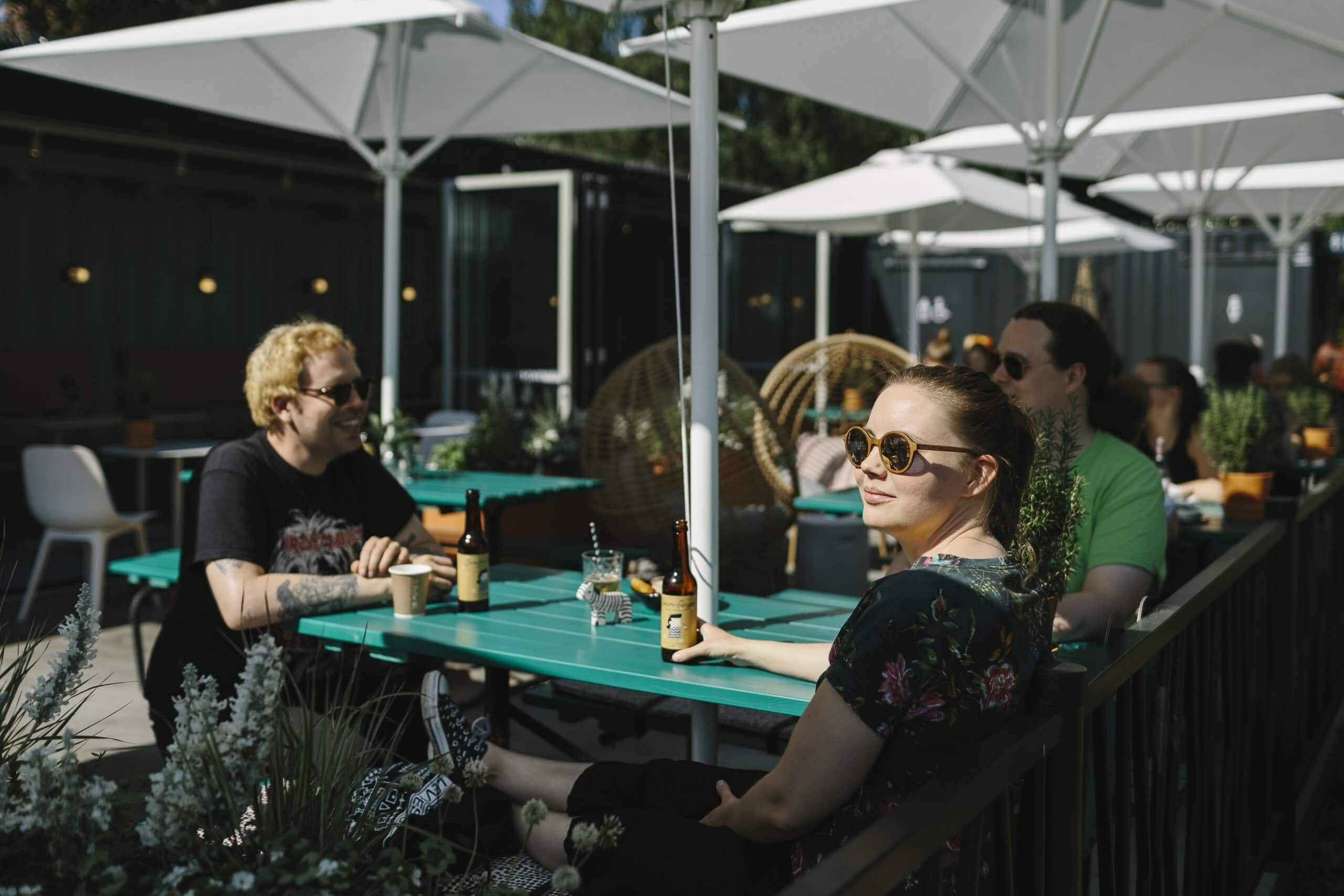 Ihmisiä drinkillä Joensuun Konttiravintola Mortonin aurinkoisella terassilla.